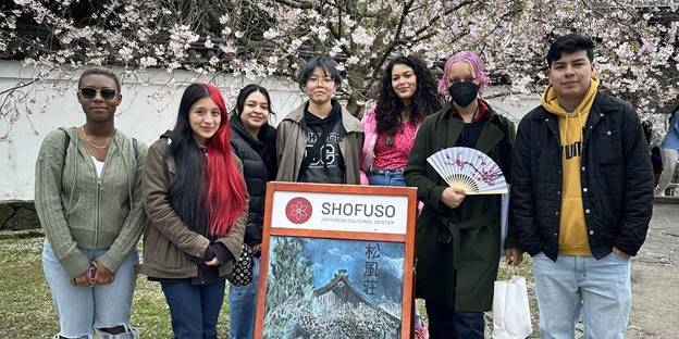 Students gather for a picture outside under a cherry blossom
