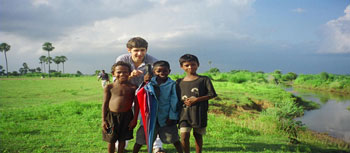 Skidmore student, Alex Tzelnic '07and kids outside a nearby school in Sujata Village