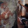 Conservator Angelyn Bass cleans and stabilizes the surface of a wall of a Maya house that dates to the 9th century A.D. The figure of a man who may have been the town scribe appears on the wall to her left. Excavation and preservation of the site were supported by the National Geographic Society.  Photo by Tyrone Turner c. 2012 National Geographic