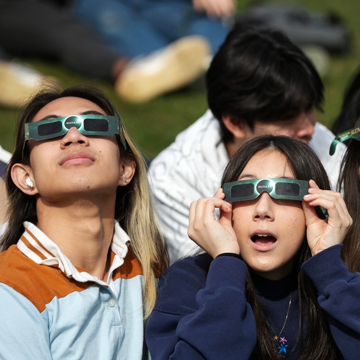 Two+students+watch+the+eclipse+through+Skidmore-branded+glasses.