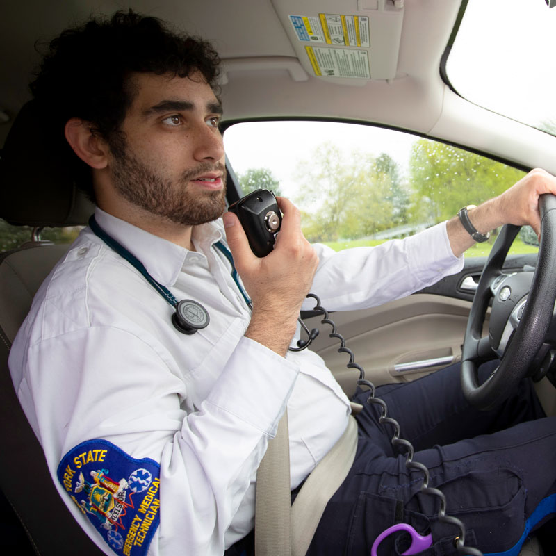 Student EMT speaking into a radio while driving a Skidmore emergency response vehicle.