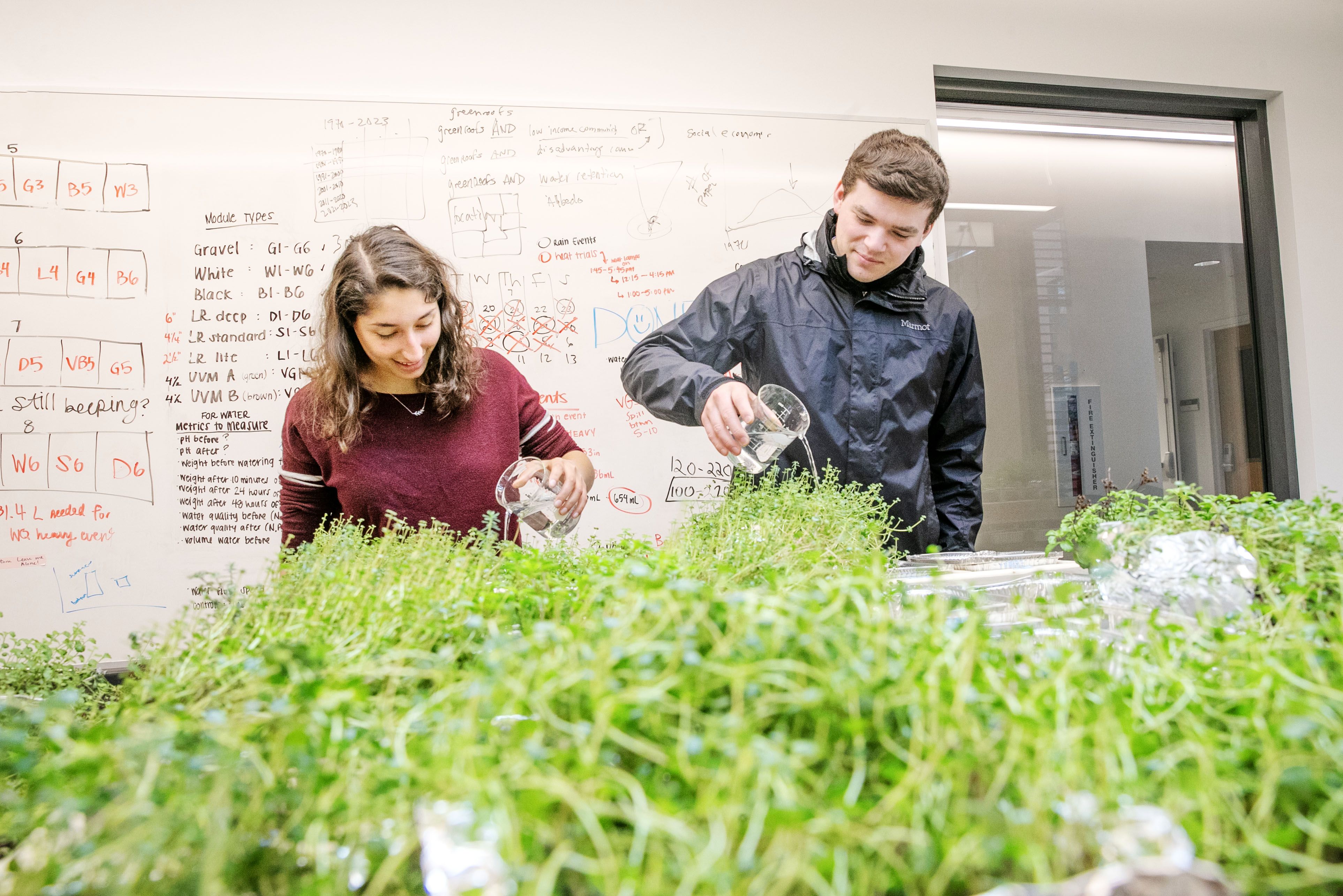 Environmental science majors Kaitlin Katirachi ’24, left, and environmental studies major Jackson Smith ’24 water plants as part of a capstone project on green roofs that their group presented at Academic Festival.