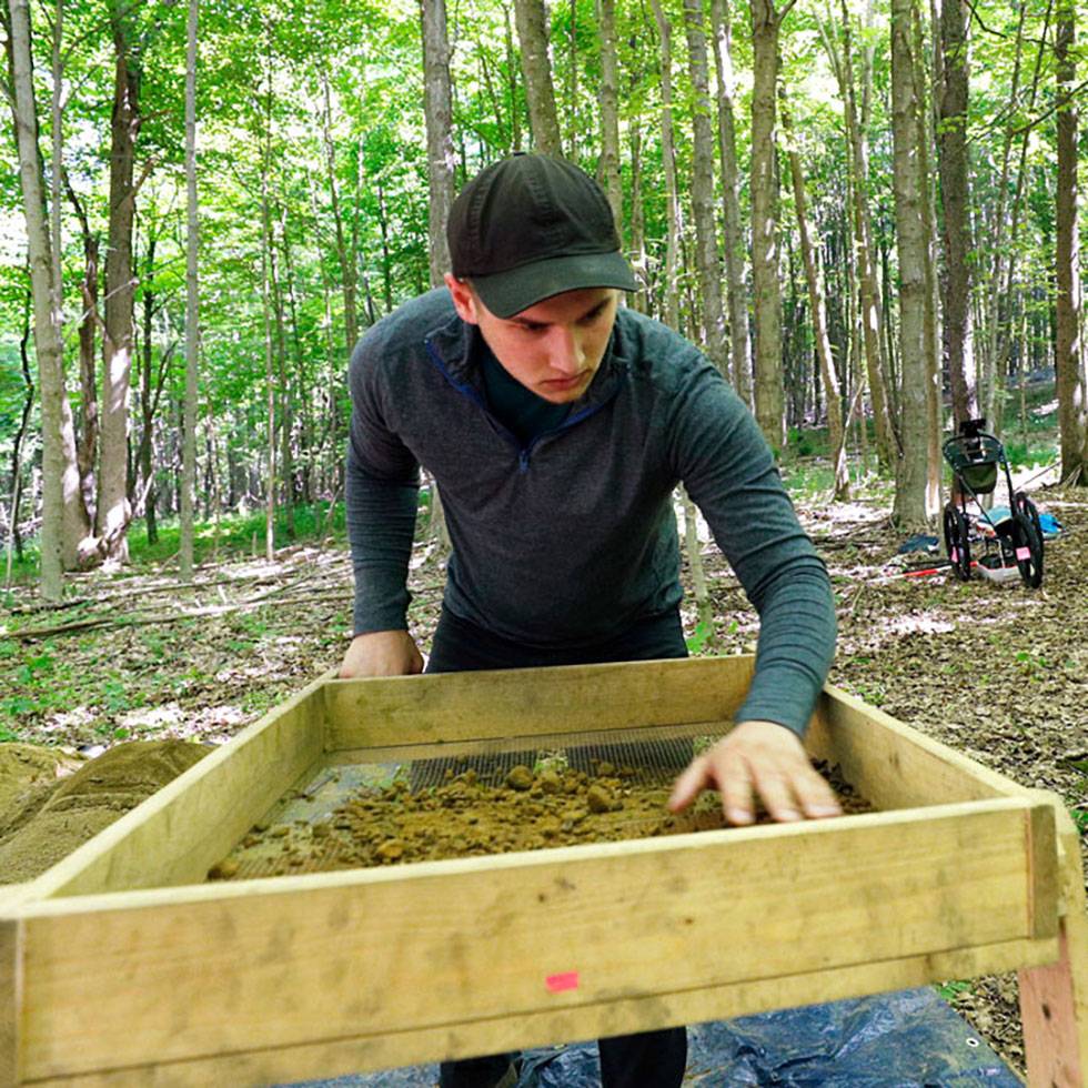 A student excavating an archaeology site in Skidmore's North Woods that was once home to a Revolutionary War family farm and estate.