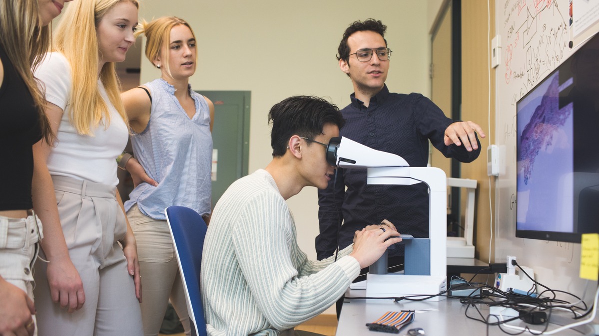 A student uses the SmartScope microscope under Carney's direction as others watch.