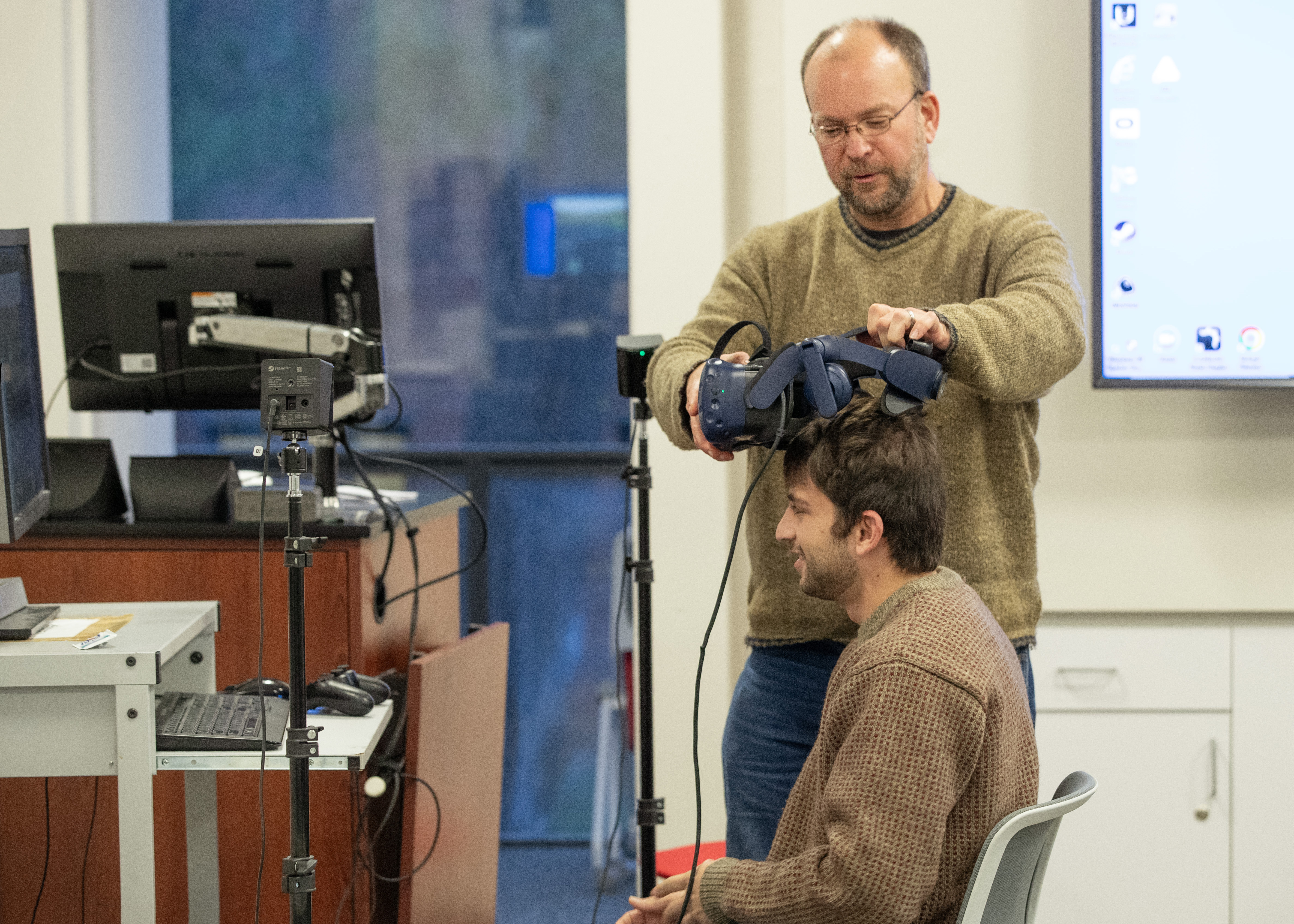 Ben Harwood assists a student in equipping the VR goggles.
