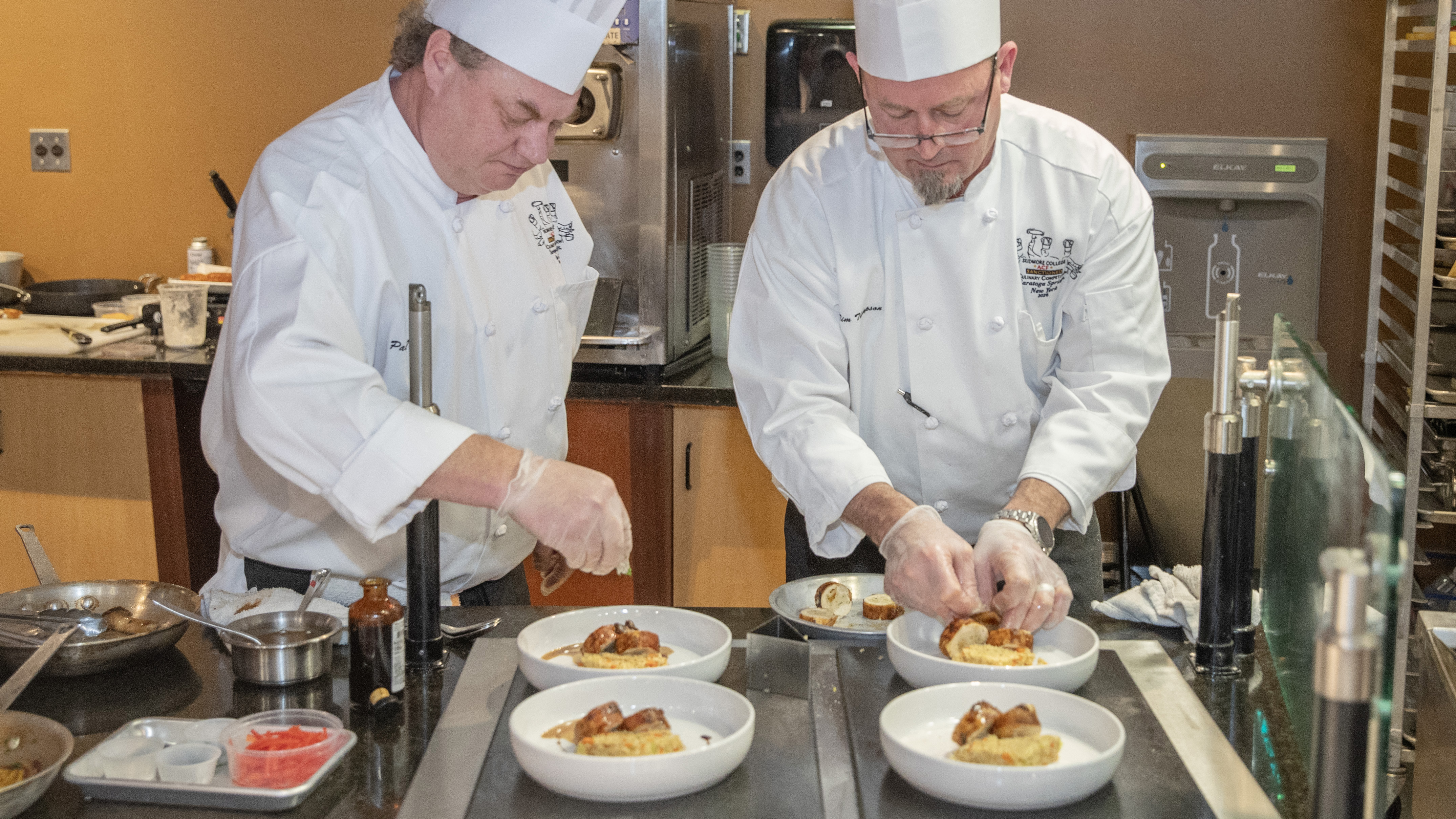 Production Manager Tim Thompson and Senior Cook Paul Karlson plate their appetizer, Cornish game hen ballotine with king trumpet demi glaze over brown rice.