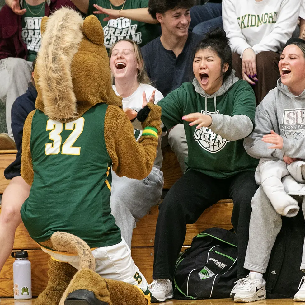 Skidmore’s Thoroughbred mascot high-fives spirited students in the bleachers at the annual Big Green Scream athletic event.