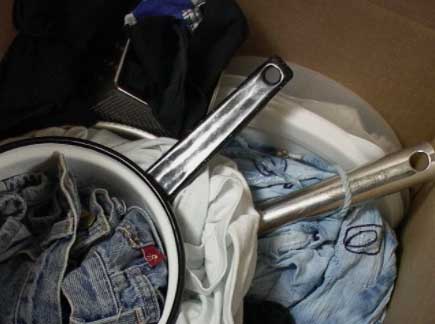 pans and clothes nestled together in a moving box