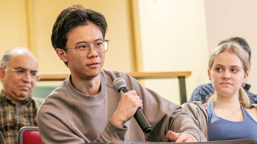 A student holds a microphone during a presentation in Davis auditorium 