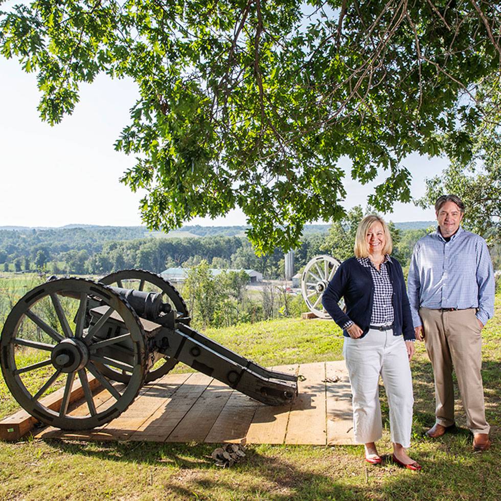 Professors Natalie Taylor and Tillman Nechtman stand next to a cannon at the Saratoga Battlefield.