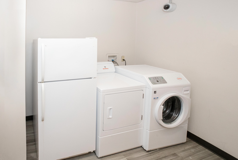 Laundry area with a refrigerator, dryer, and front-loading washing machine.