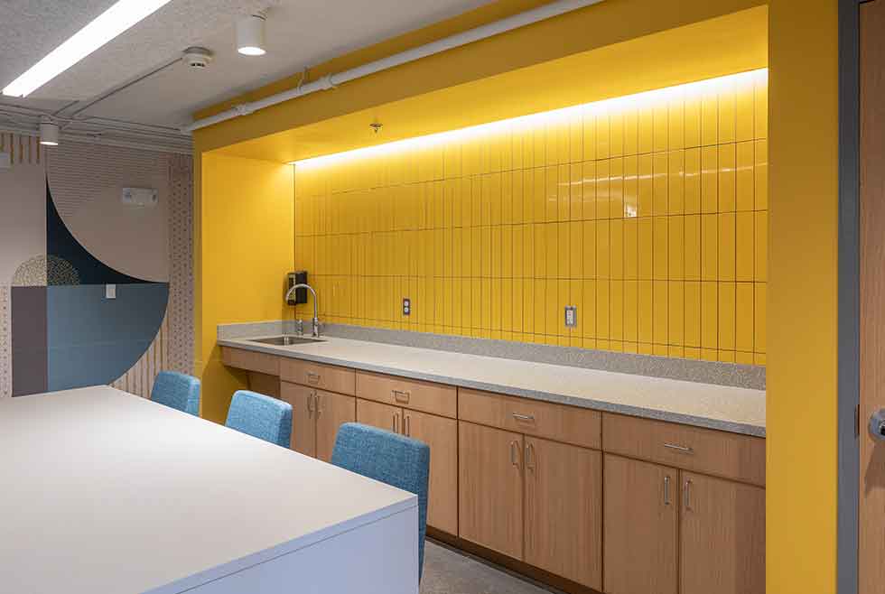 Jonsson residence kitchenette with a yellow tile backsplash, sink, counter space, cabinets, and seating.