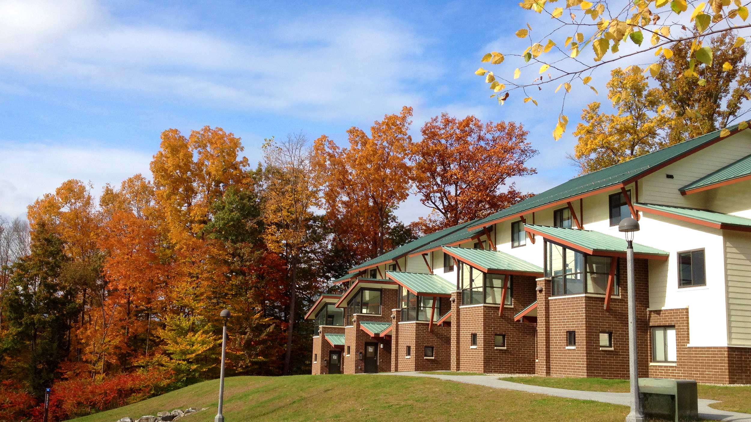 Skidmore apartment-style residences with green roofs set against bright orange fall foliage.