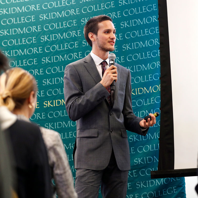 Student presenting a business pitch with a microphone at Skidmore’s Freirich Entrepreneurship Competition.