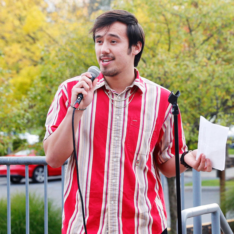 Student holding a microphone and speaking at an outdoor event, representing Skidmore’s Student Government Association.