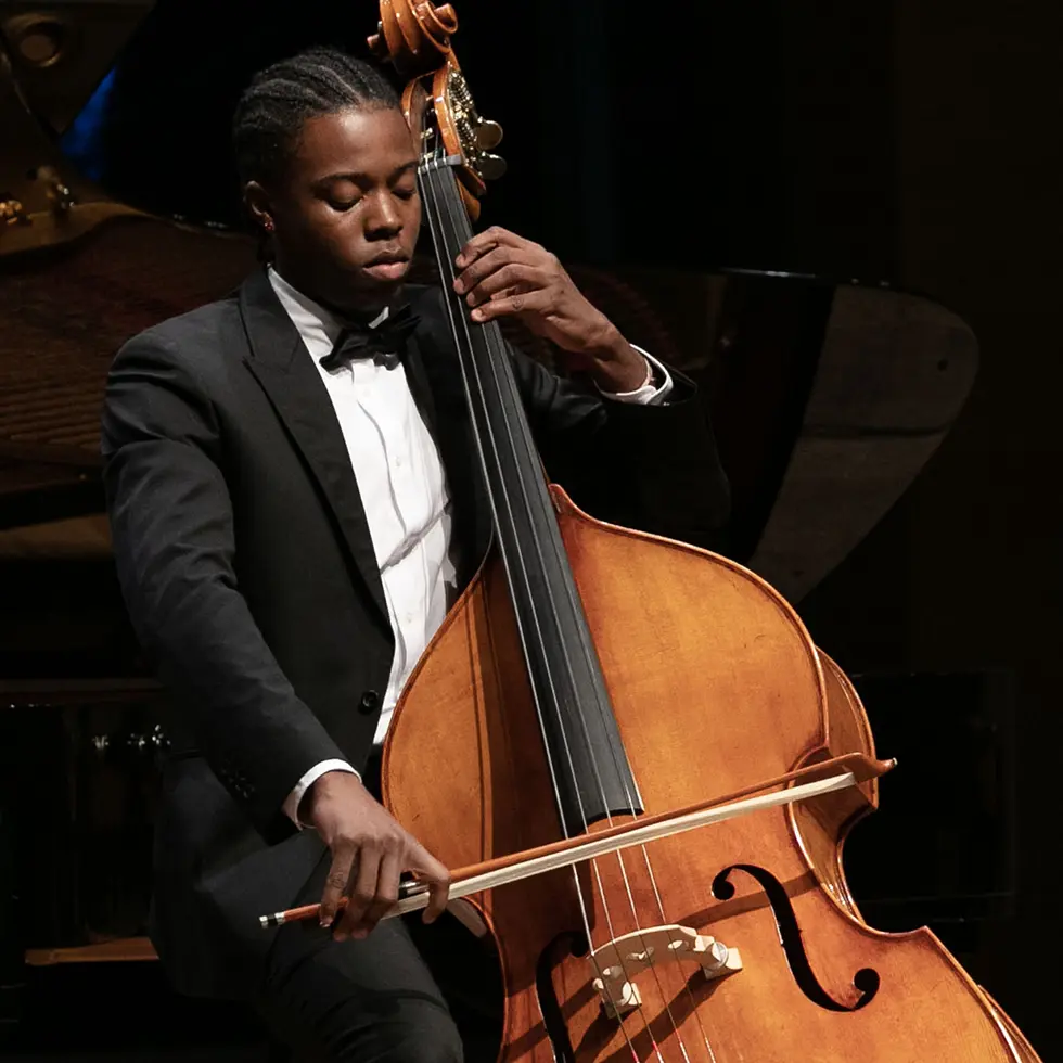 A young man plays a string bass on stage