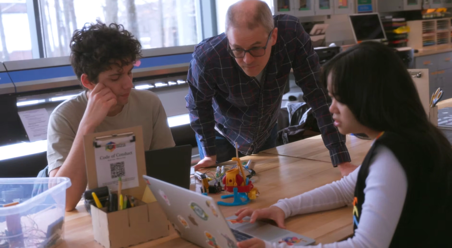Professor mentoring two students working on a hands-on engineering or robotics project in a collaborative, tech-equipped makerspace at Skidmore College.