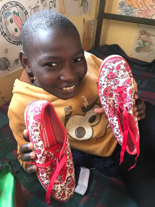 Kenyan child holding a new pair of shoes
