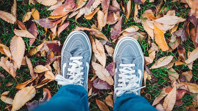 A photo looking down at men's feet in a pile of leaves