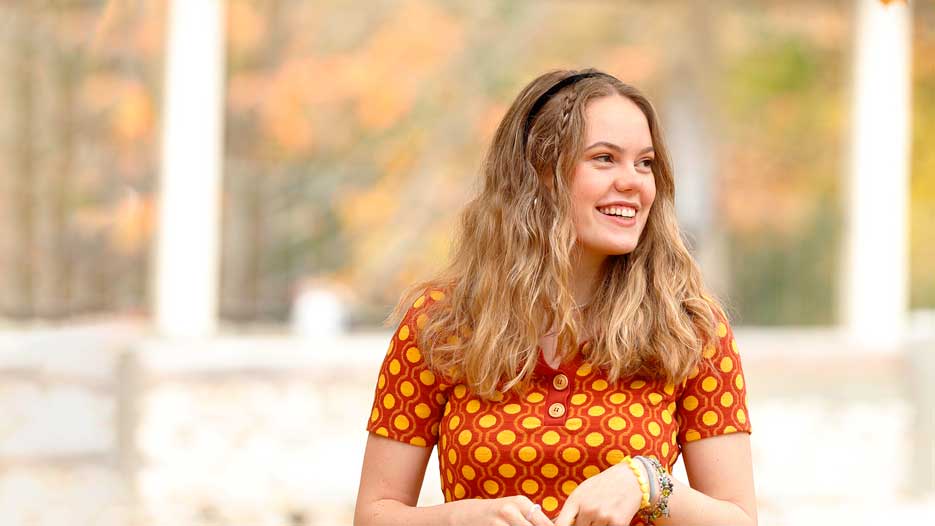 A young woman with blonde hair walks outside on a fall day