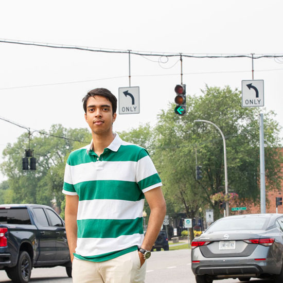Skidmore+student+Azizul+Hakim+stands+in+front+of+a+traffic+light+as+cars+travel+by+in+the+distance.+