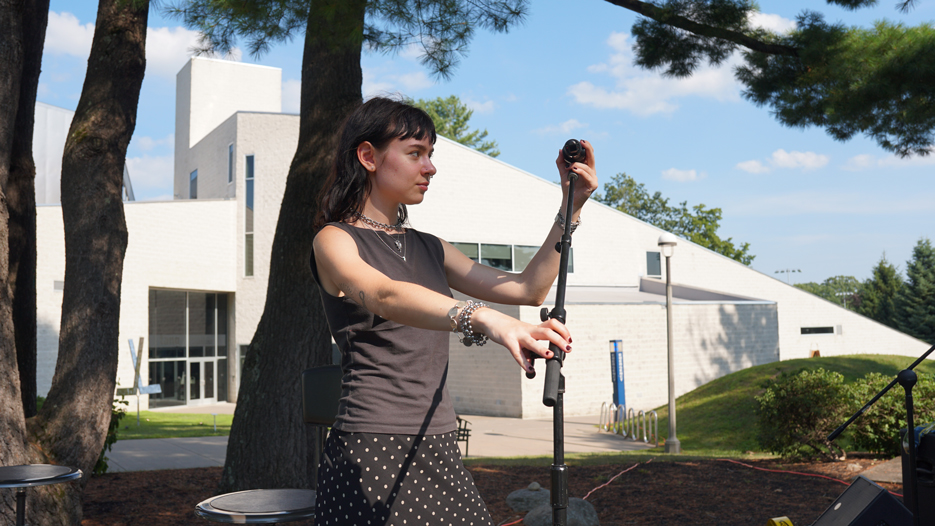 Elio Gottschalk ’26 sets up a microphone for the Upbeat on the Roof concert series on the Tang Teaching Museum lawn