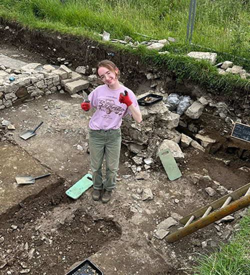 Student+Aimee+Holland+%E2%80%9925+stands+in+an+excavation+site.