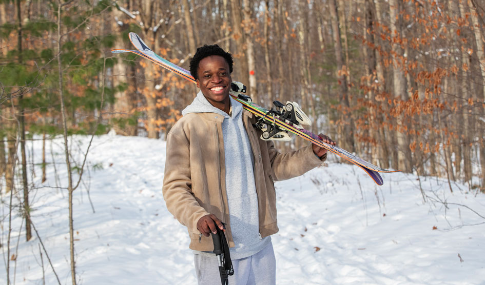 Suleiman Lailati ’28 holds a pair of skis over his shoulder. 