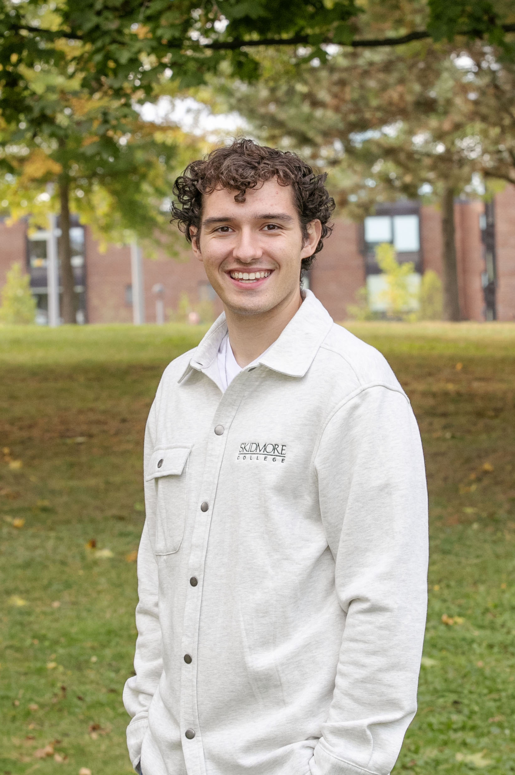 Braedon stands outside in Skidmore memorabilia, smiling. 