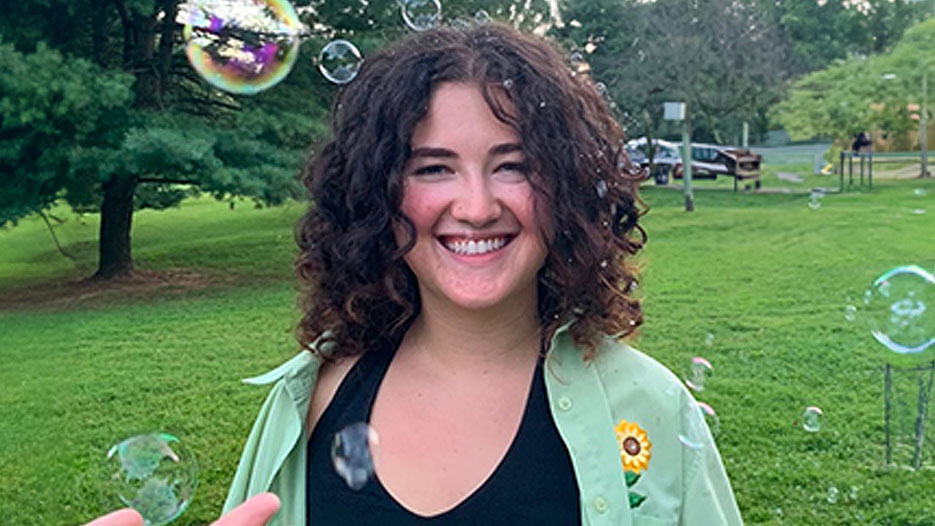 Eva smiles in an outdoor setting surrounded by bubbles