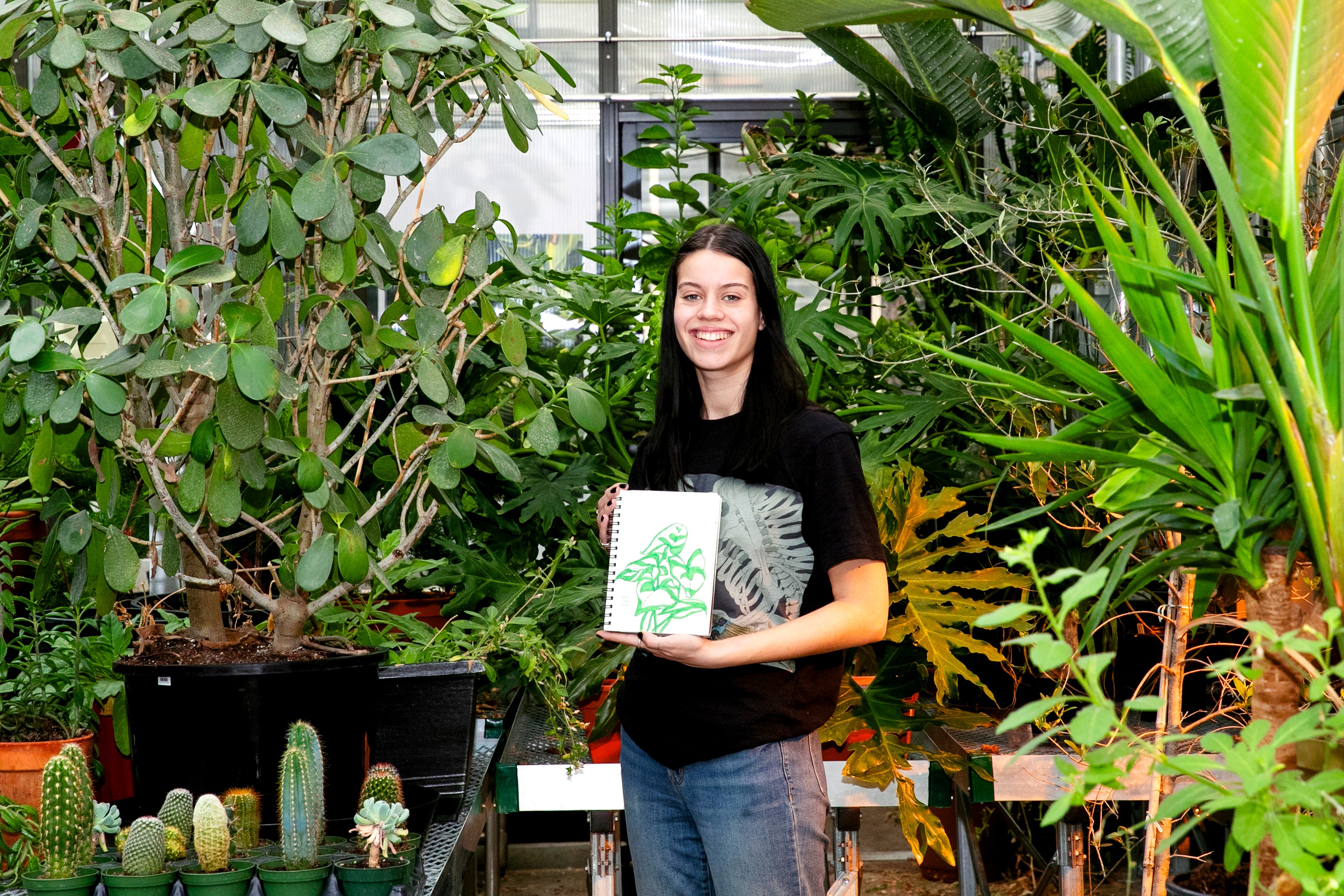 Biology and studio art double major Allison Conwell ’25, who plans to pursue a career in scientific illustration, shows one of her illustrations during a visit to the Billie Tisch Center for Integrated Sciences greenhouse.