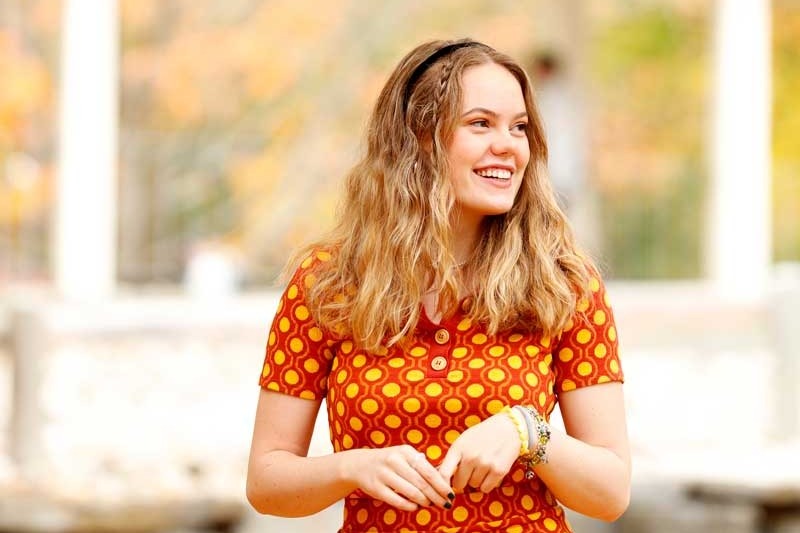 A young woman with blonde hair walks outside on a fall day 