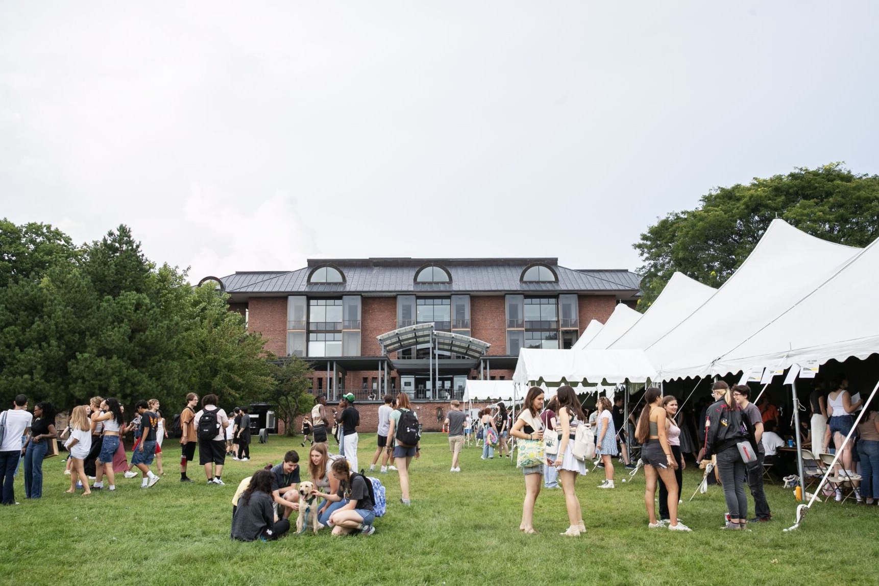 Students roam and chat outside of the Club Fair tents. You can see Lucy Scribner Library centered in the background.