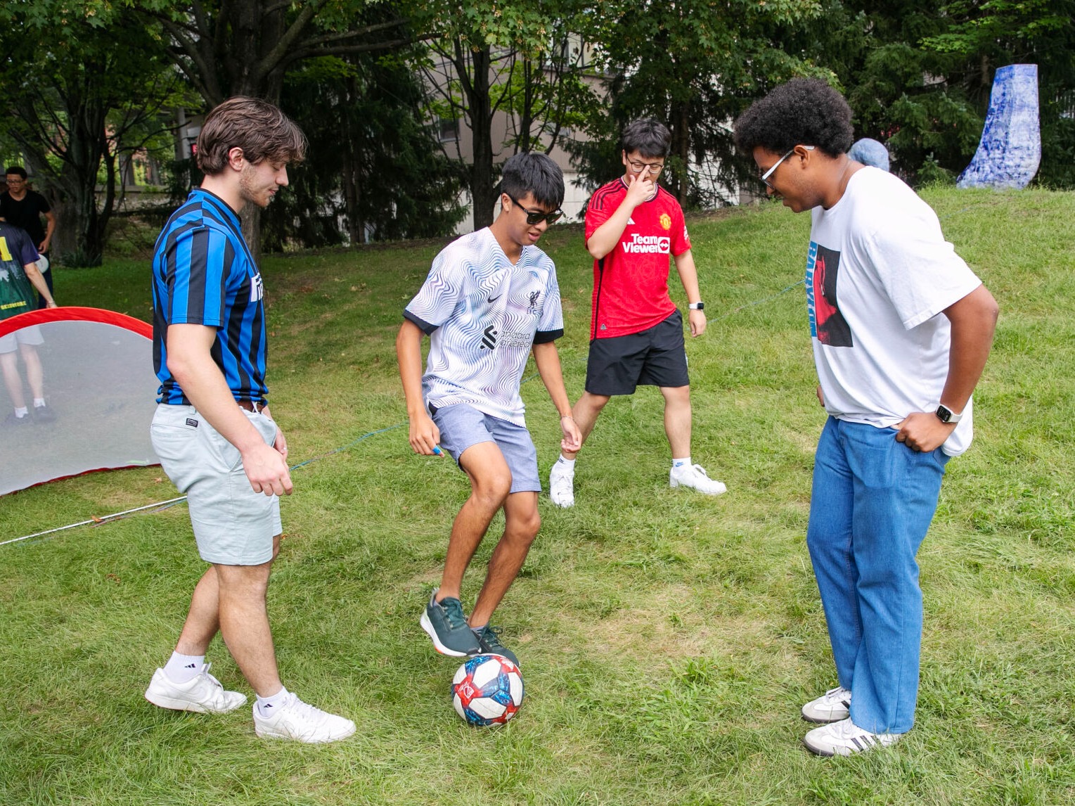 Four students play soccer on Skidmore's South Lawn.