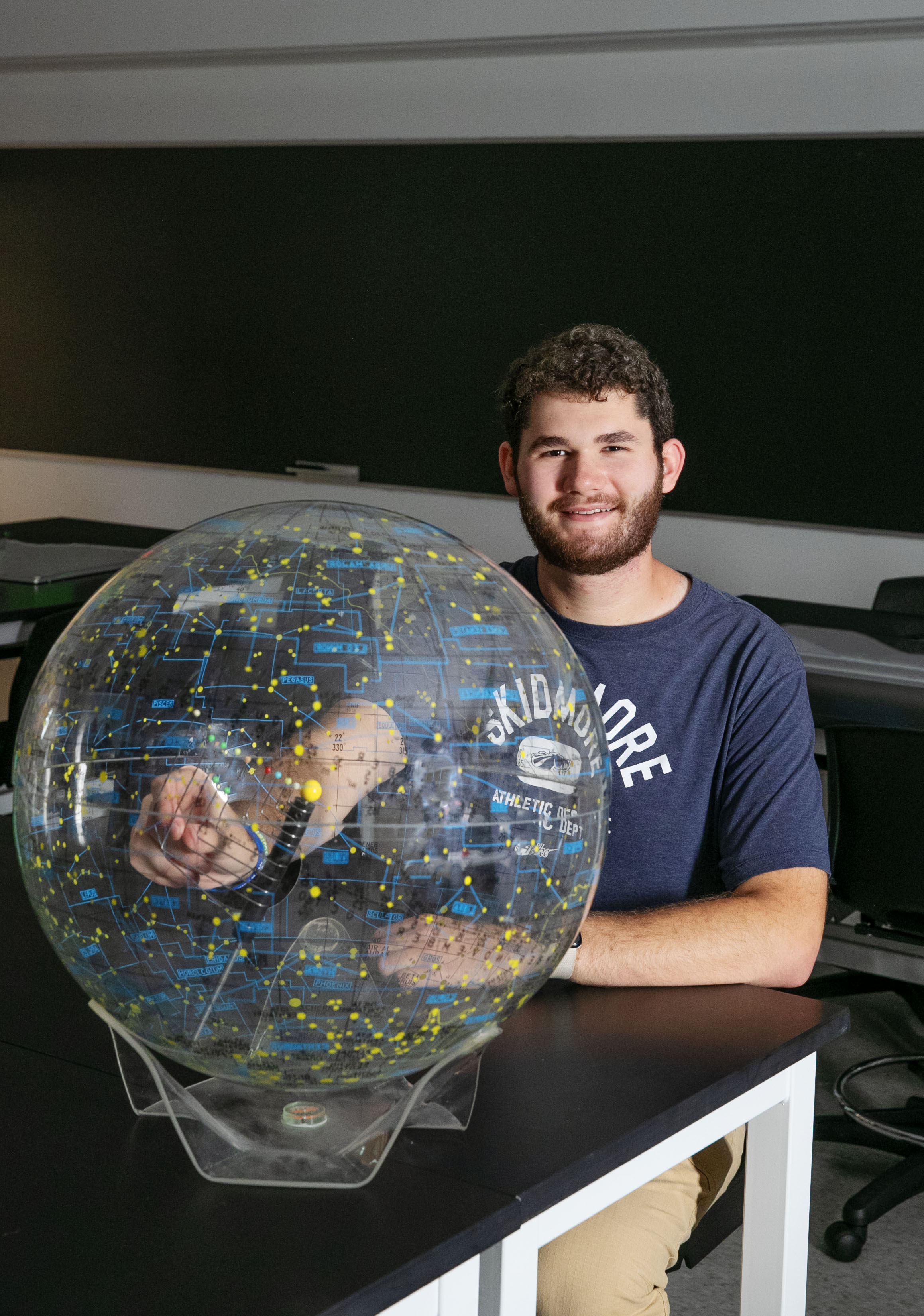 Milo Flamenbaum ’26 sits beside a plastic globe.