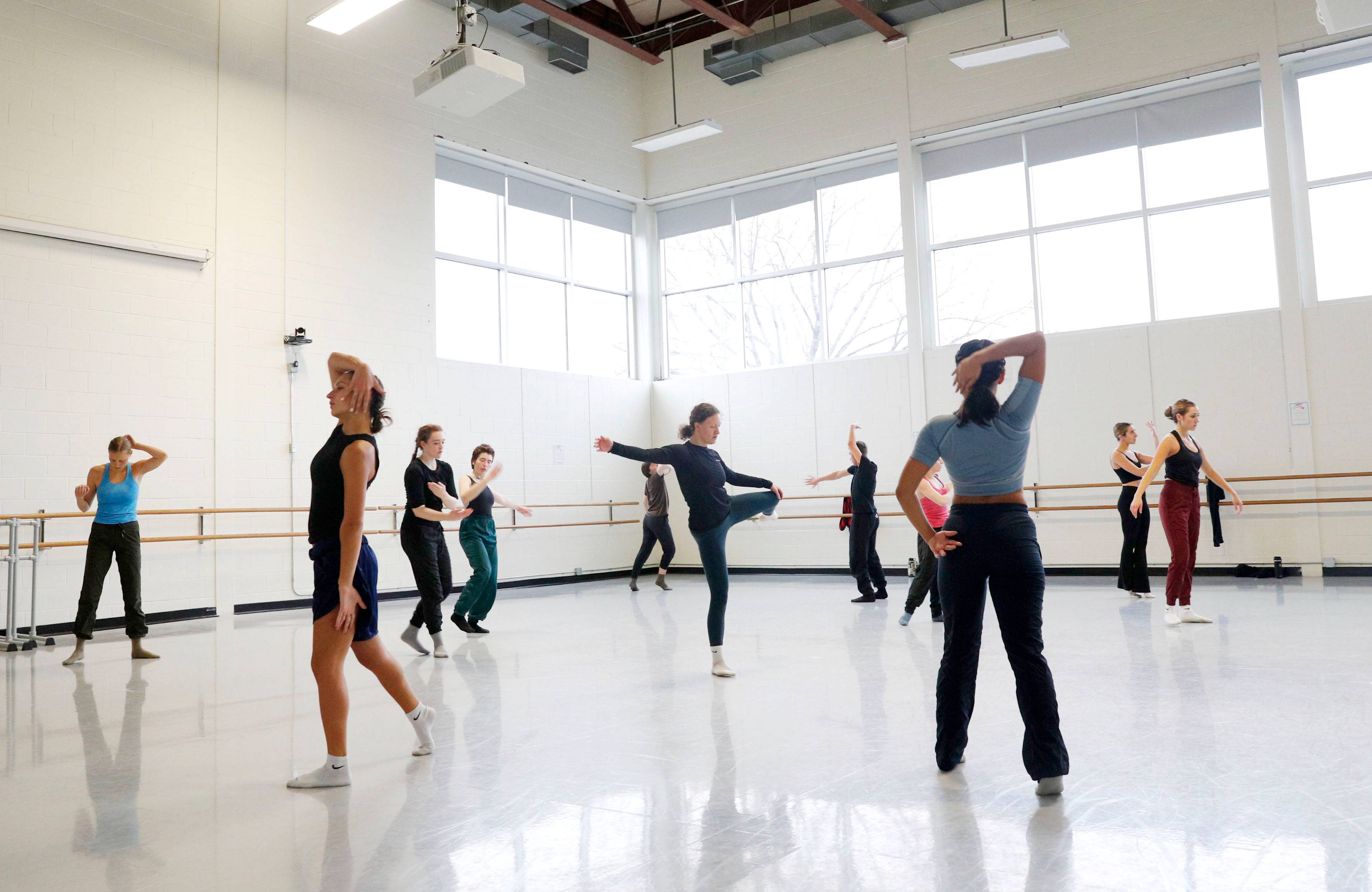 A dozen dancers practice in a white dance student