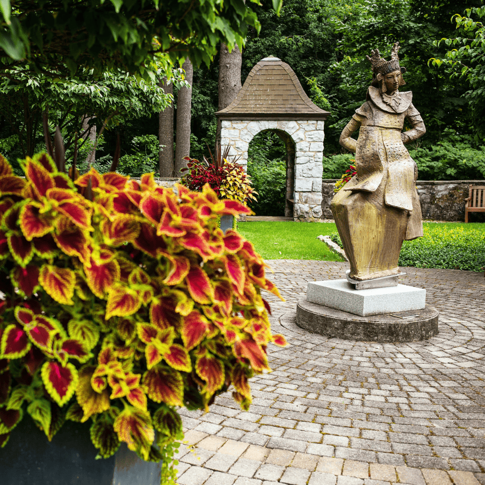 View of Alumni Memorial Garden with vibrant yellow and red plant and sculpture in the background