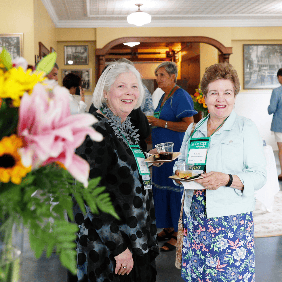 Two smiling alumni at a President's Society event hosted in the Scribner Carriage house.