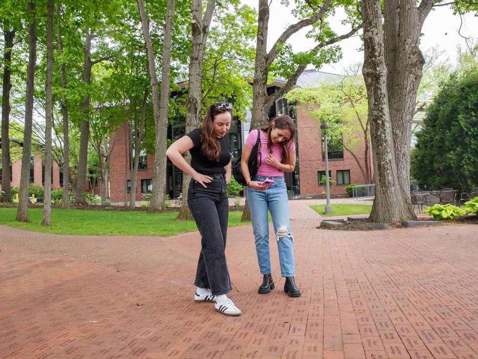 Two alumni look down at the alumni engraved brick walkway in Case Green