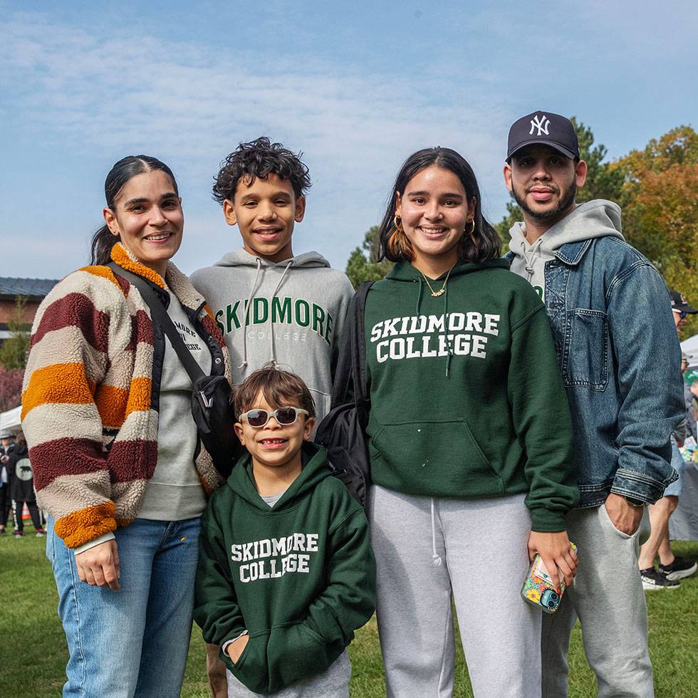 A family poses together outside on Case Green wearing Skidmore sweatshirts