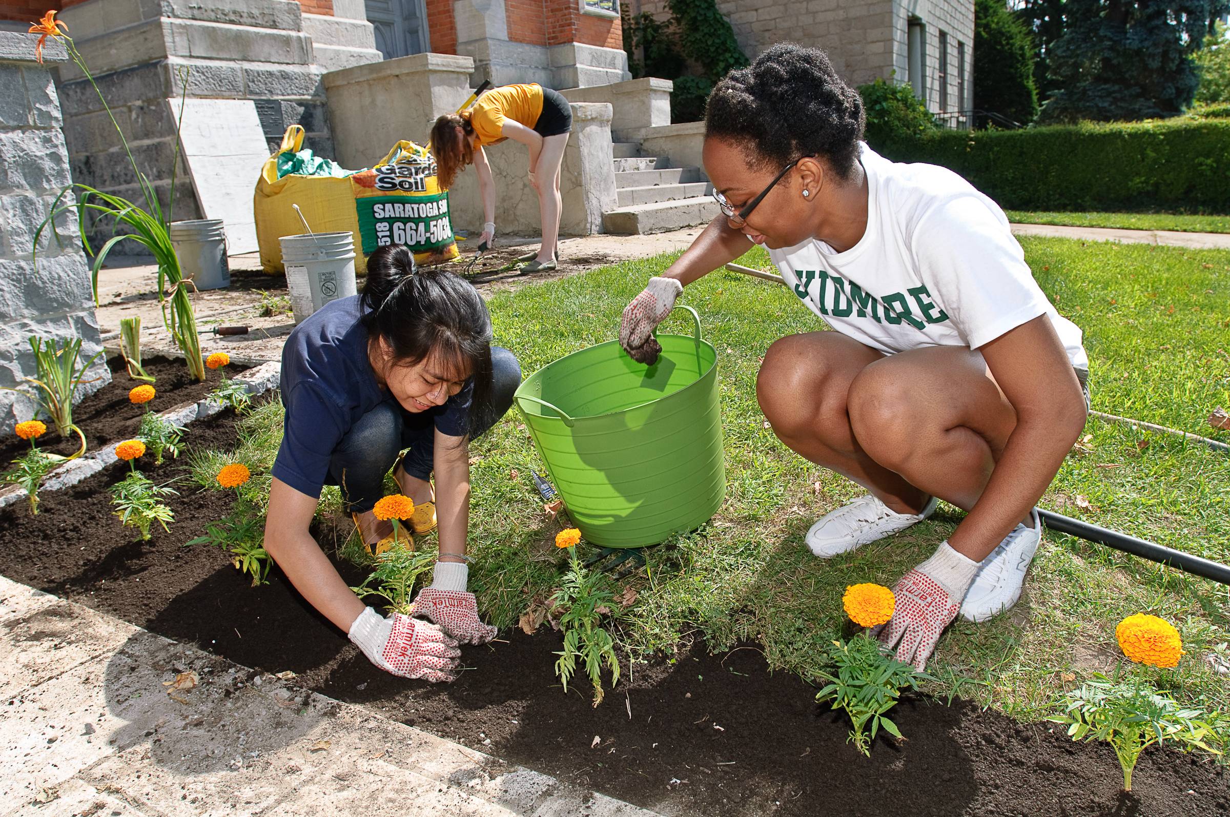 Two people work together to plant flowers as volunteers