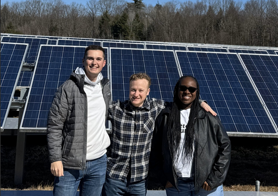 3 students standing in front of some solar panels