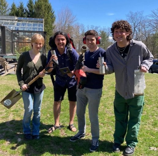 4 students standing outside with gardening tools
