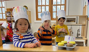 Children in play bakery wearing chefs hats
