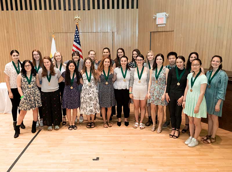 22 students pose for a group photo all wearing medals