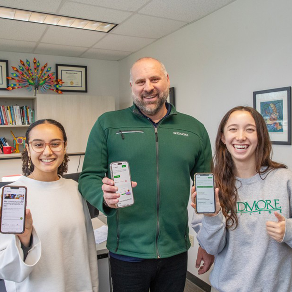 A professor and two students holding cell phones