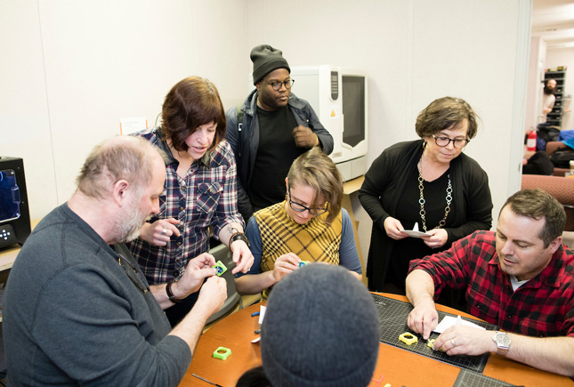staff and faculty work together  to create a battery operated miniature construction cone during an open house at The Hub