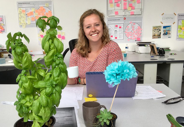 Student smiles from her desk at an internship