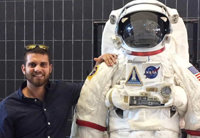 Student poses with a NASA space suit