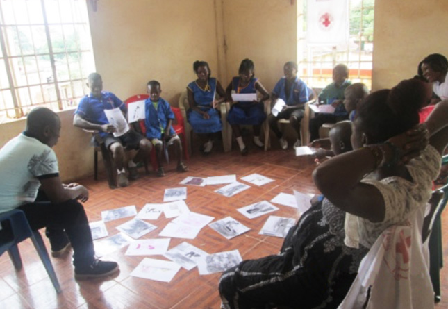 Student runs a meeting of people in a small room in Sierra Leone, Africa